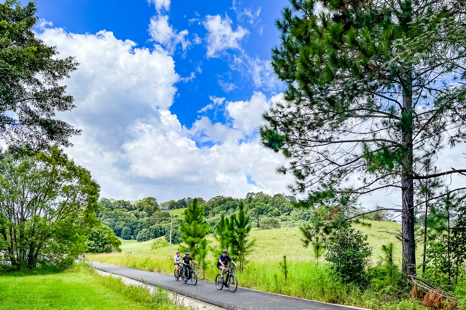 A group of friends riding e-bike along the luscious Northern Rivers rail trail.  e bike hire at mooball